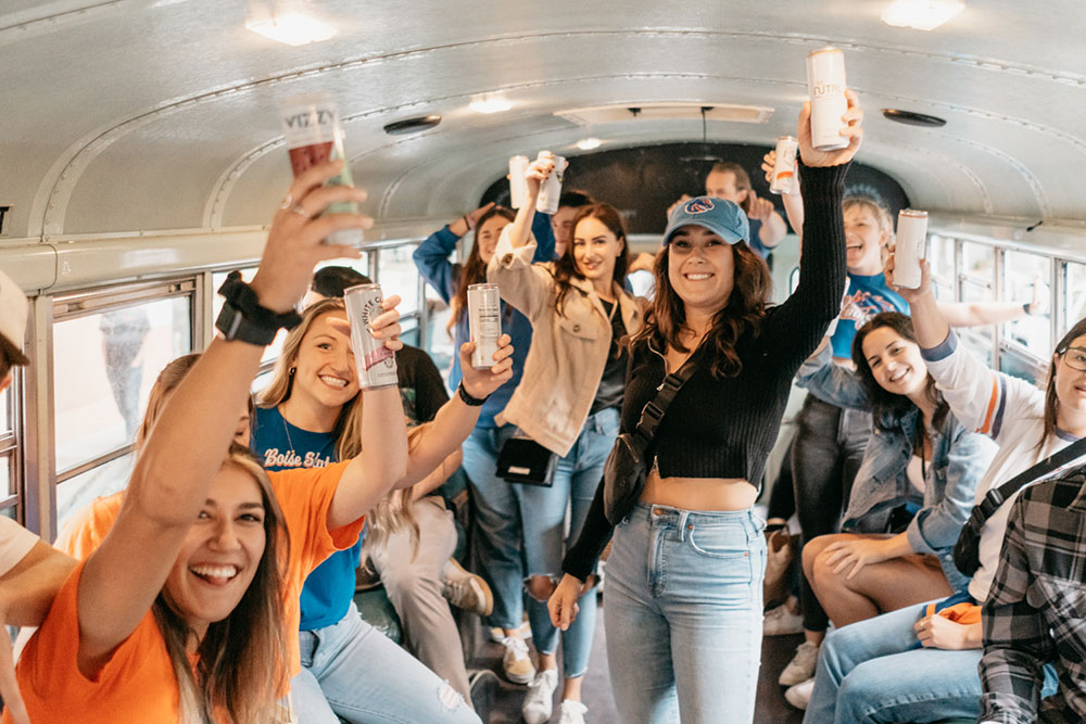 Group in Boise State gear raising drinks aboard the party bus