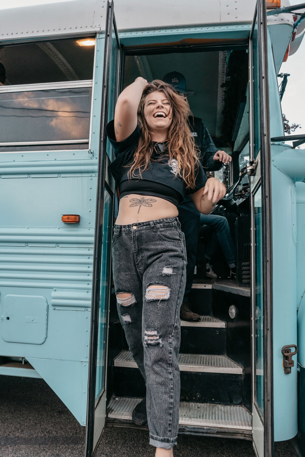 Guest laughing in the open doorway of the party bus at dusk