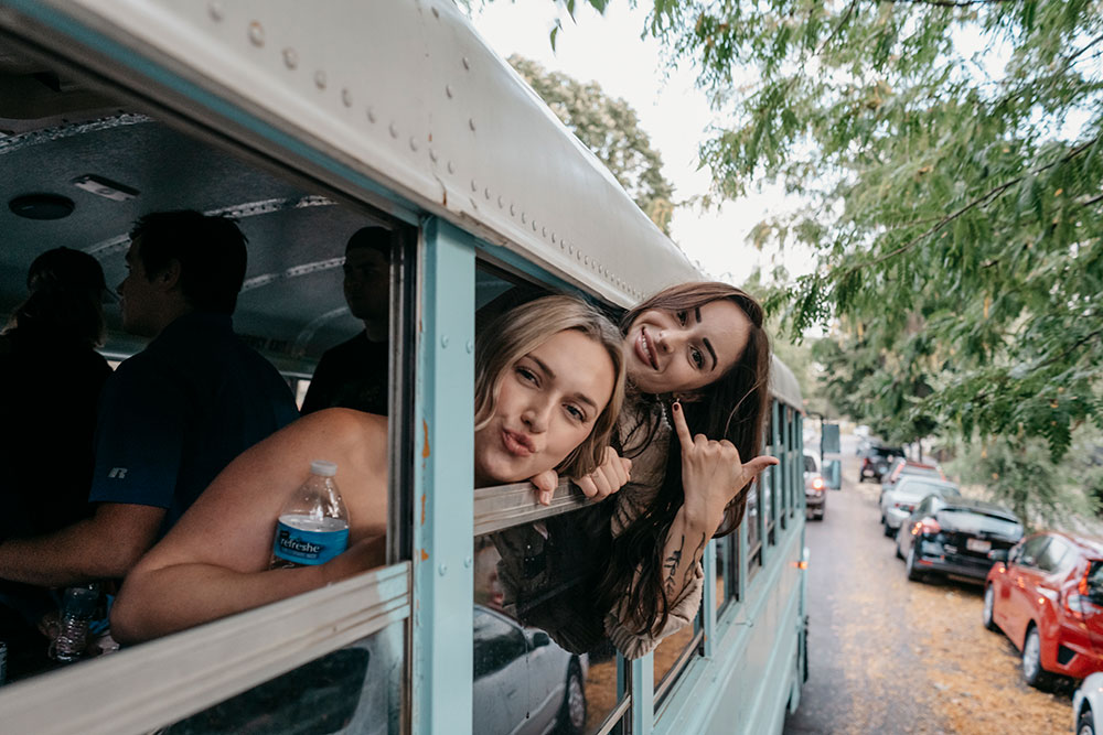 Two guests leaning out the party bus window on a Boise street