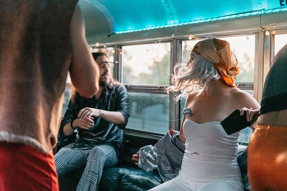 Guests relaxing on the party bus bench seats under teal interior lights