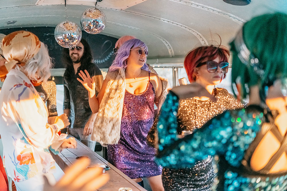 Disco themed group in sequins under disco balls on the party bus