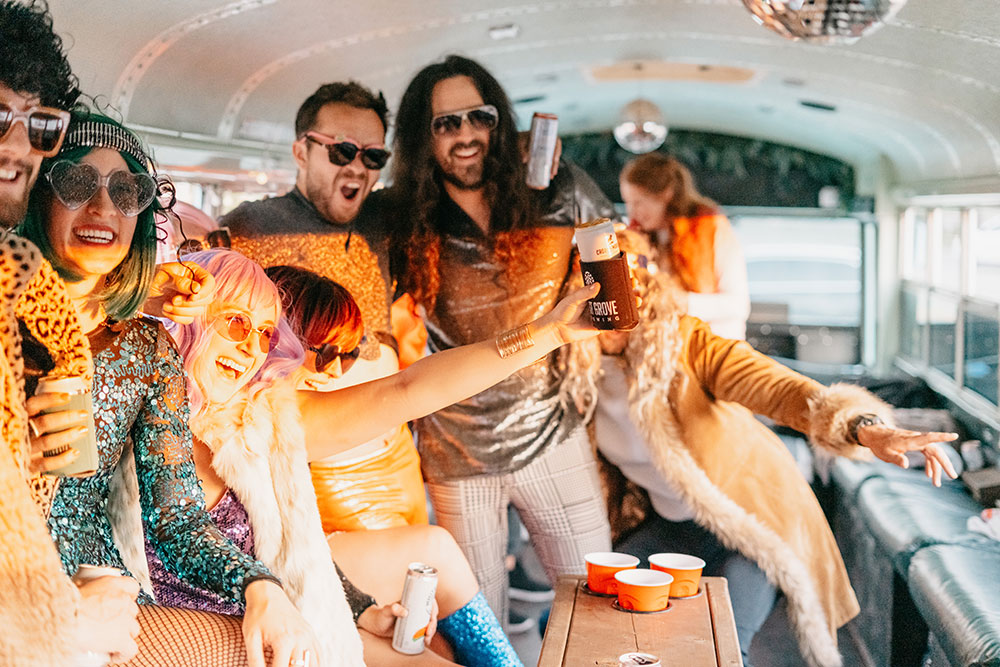 Seventies themed group toasting drinks around the party bus table