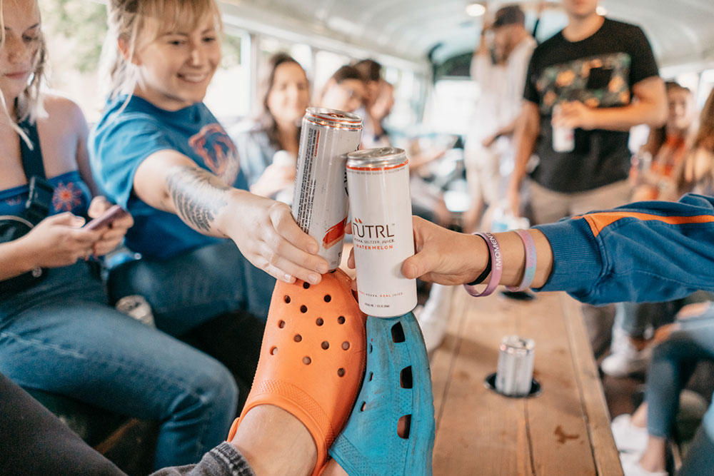 Close up of guests toasting seltzer cans over the party bus table